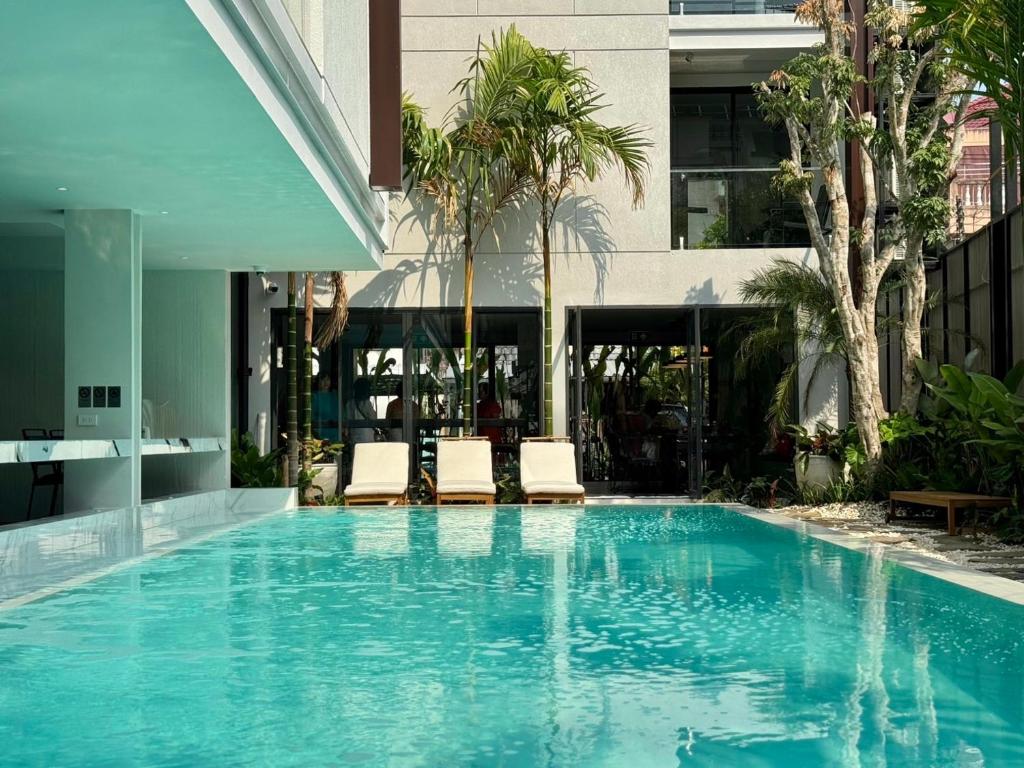 a swimming pool with two chairs and a building at POR Singharat in Chiang Mai