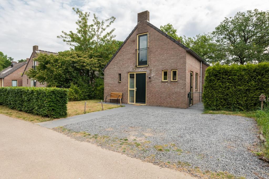 een stenen huis met een bank ervoor bij Het Huys Ewijk mooi luxe en een laadpaal in Ewijk