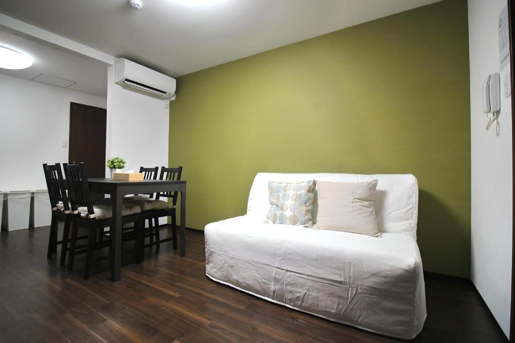 Yagara Terrace House D في أوساكا: غرفة معيشة مع أريكة بيضاء وطاولة