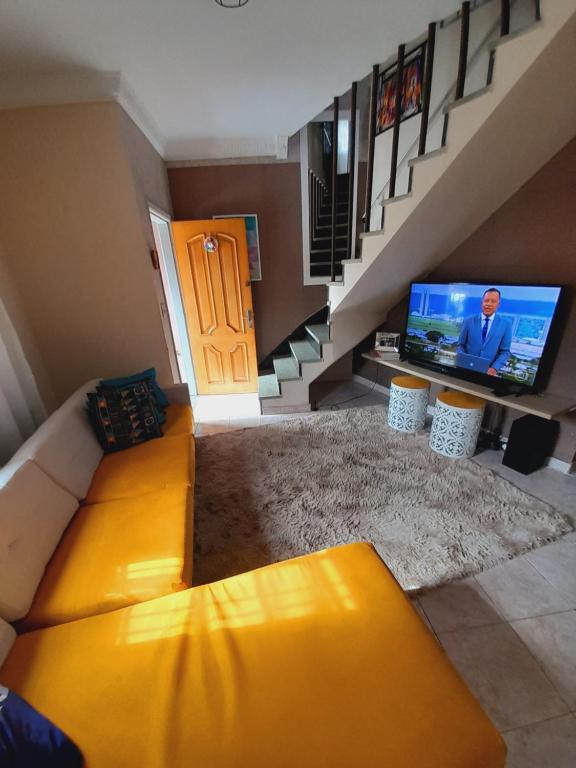 a living room with a yellow couch and a television at Casa do Luis in Sao Paulo