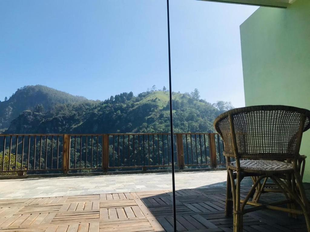 a chair on a balcony with a view of a mountain at Mandara Mount Hotel in Ella