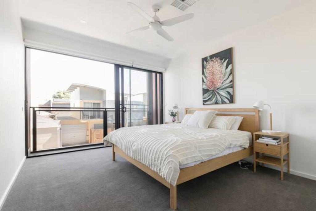 een slaapkamer met een bed en een groot raam bij Vinrace City Escape in Adelaide