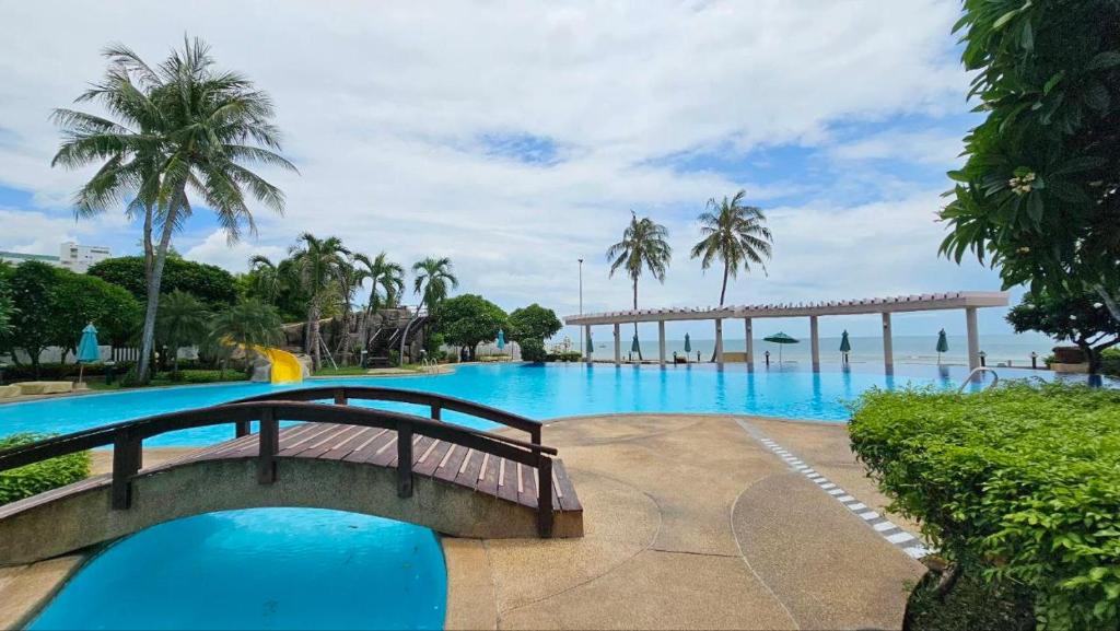 a large swimming pool with a bridge and palm trees at Baan Sansaran Excellent apartment on the beach with a large territory and swimming pools. in Hua Hin