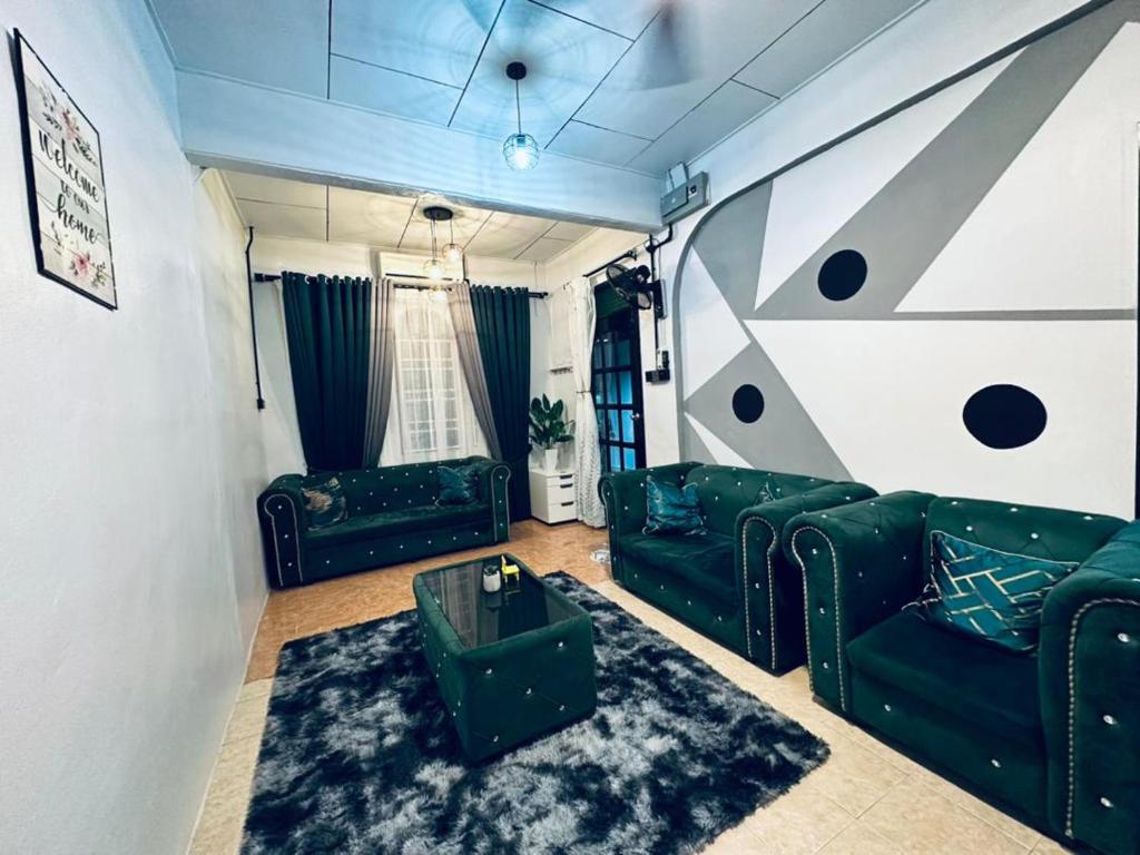 a living room with green couches and a couch at Kuu Inn Homestay Tmn Sri Wang Fasa 2 in Arau
