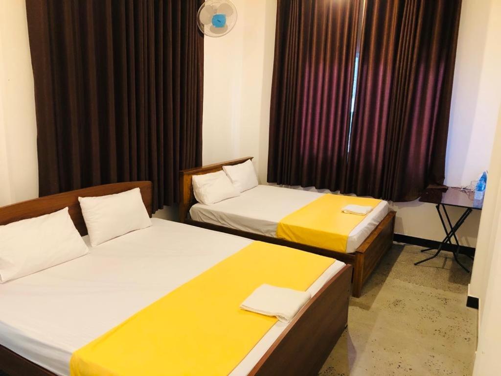 um quarto de hotel com duas camas e uma janela em Lotus cool hotel and restaurant em Ibbagomuwa