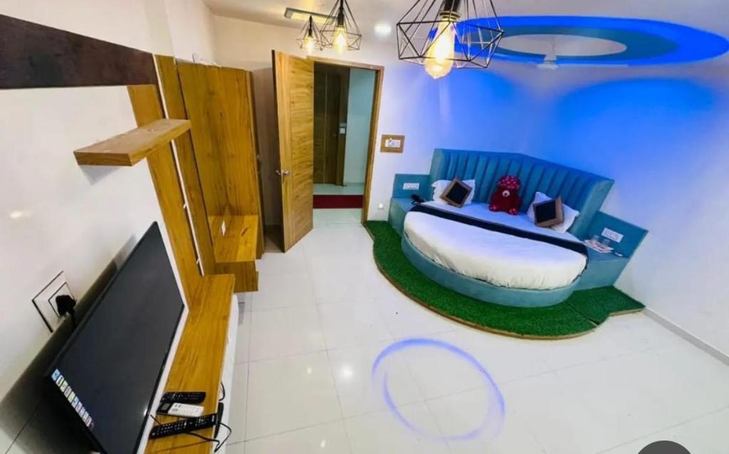sypialnia z niebieskim łóżkiem i telewizorem w obiekcie HOTEL GREEEN LEAF w mieście Anand