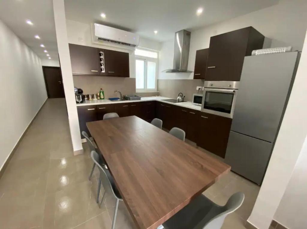 uma cozinha com uma mesa de madeira e algumas cadeiras em 4 bedroom apt 5 mins away from beach and amenities em St Paul's Bay