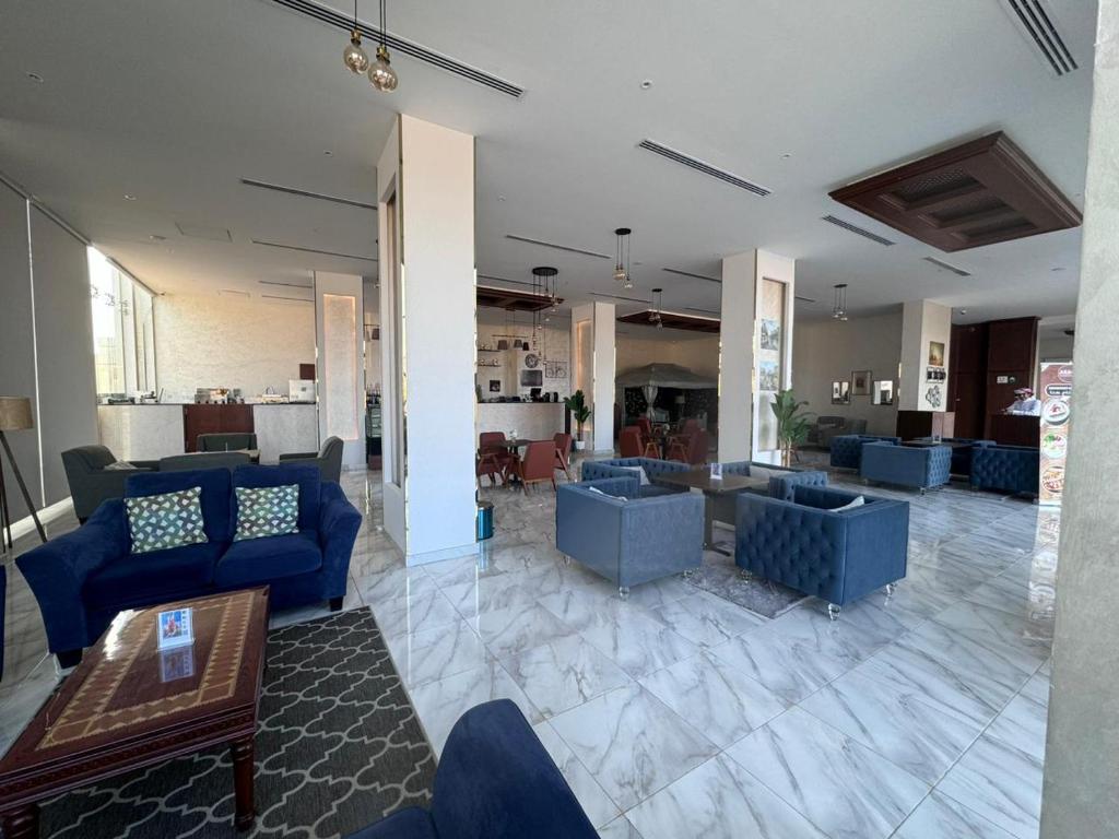a lobby with blue couches and tables in a building at بيت السلطانة للأجنحة الفندقية in Salalah
