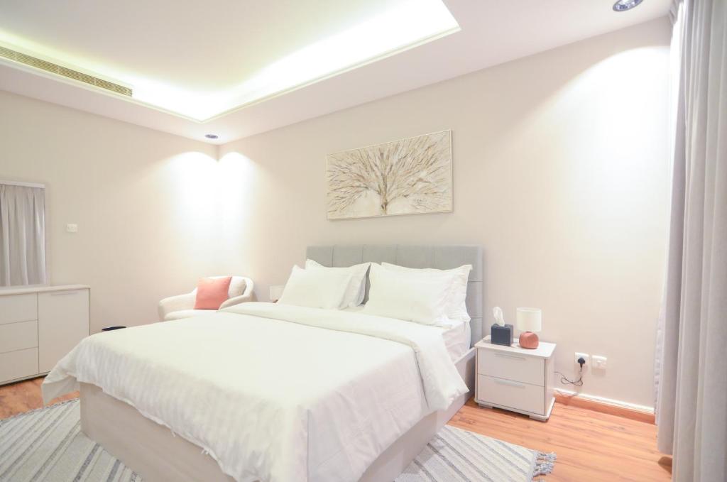 a white bedroom with a large bed with white sheets at Amas Suite in Riyadh