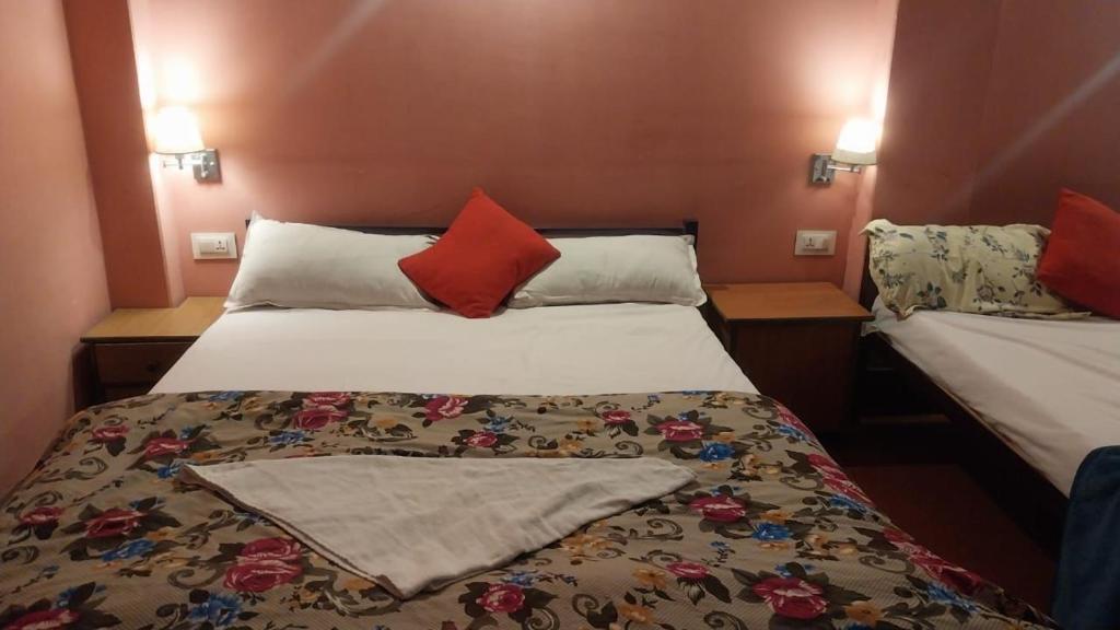 um quarto com 2 camas e almofadas vermelhas em darjeeling homestay and restuarent em Darjeeling