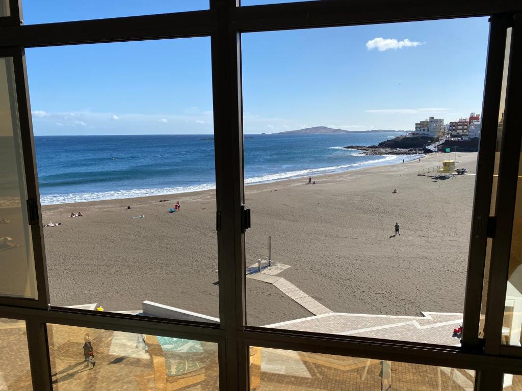 uma vista para a praia a partir de uma janela em Beachfront Apartment incl highspeed WIFI em Melenara