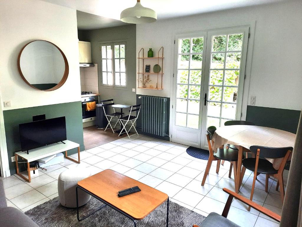 ein Wohnzimmer mit einem Tisch und einem Spiegel in der Unterkunft Magnolia Cottage in Maisons-Laffitte
