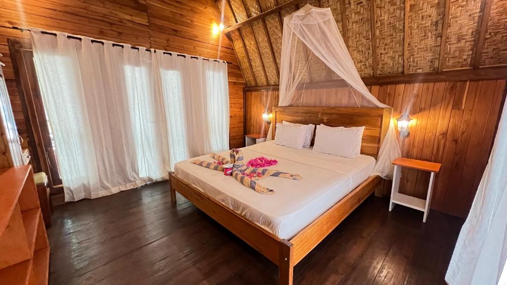a bedroom with a canopy bed with flowers on it at Gita Gili Bungalow in Gili Air