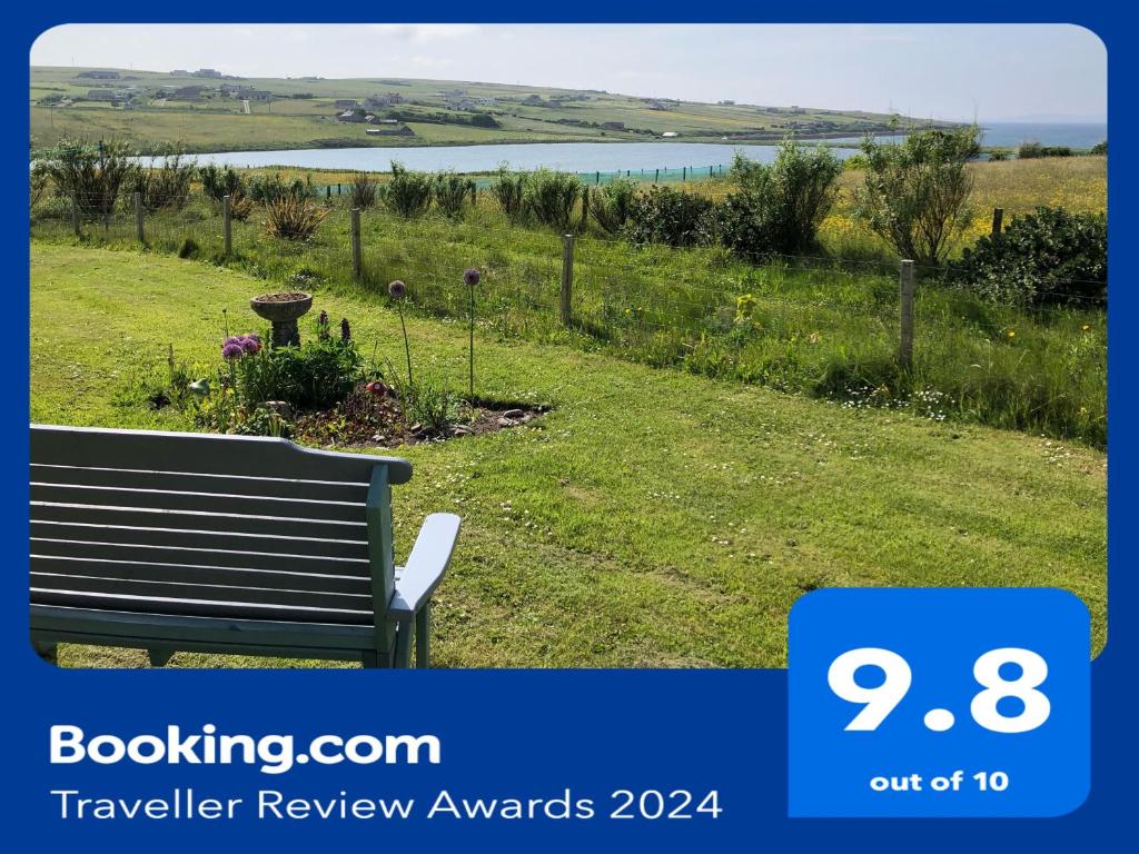 a bench in a field with a view of a lake at Old School - Exclusive 5 Room private suite in Orkney
