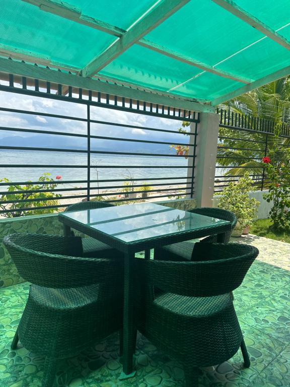 een glazen tafel en stoelen onder een pergola bij Joy o hoy beachfront house in Santander
