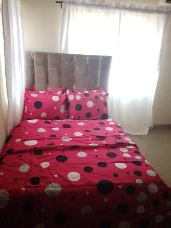 a red bed with polka dot sheets and pillows at Miraph APt. with Starlink wifi in Abuja