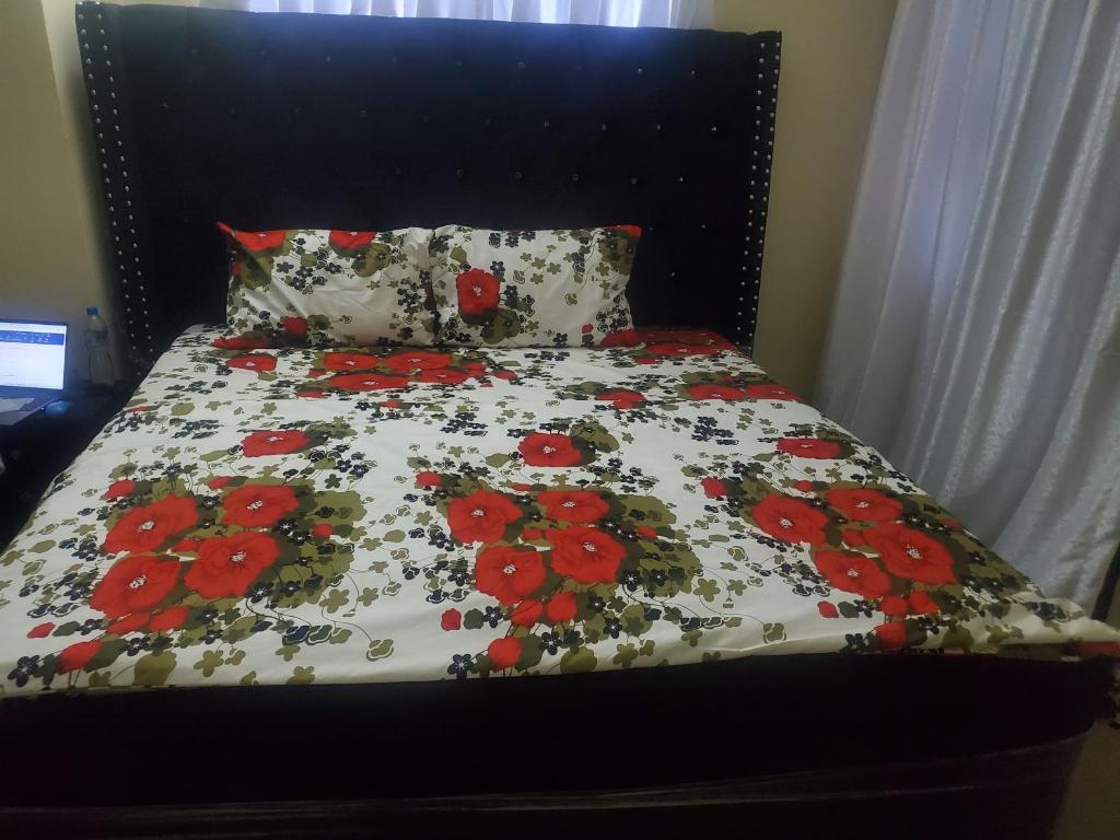 a bed with a black headboard with red flowers on it at Miraph APt. with Starlink wifi in Abuja