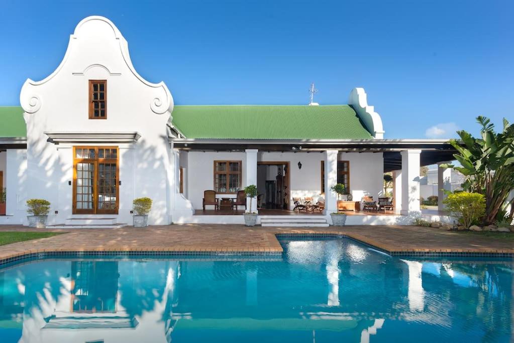 een wit huis met een zwembad ervoor bij Historical Cape Dutch Homestead in Kaapstad