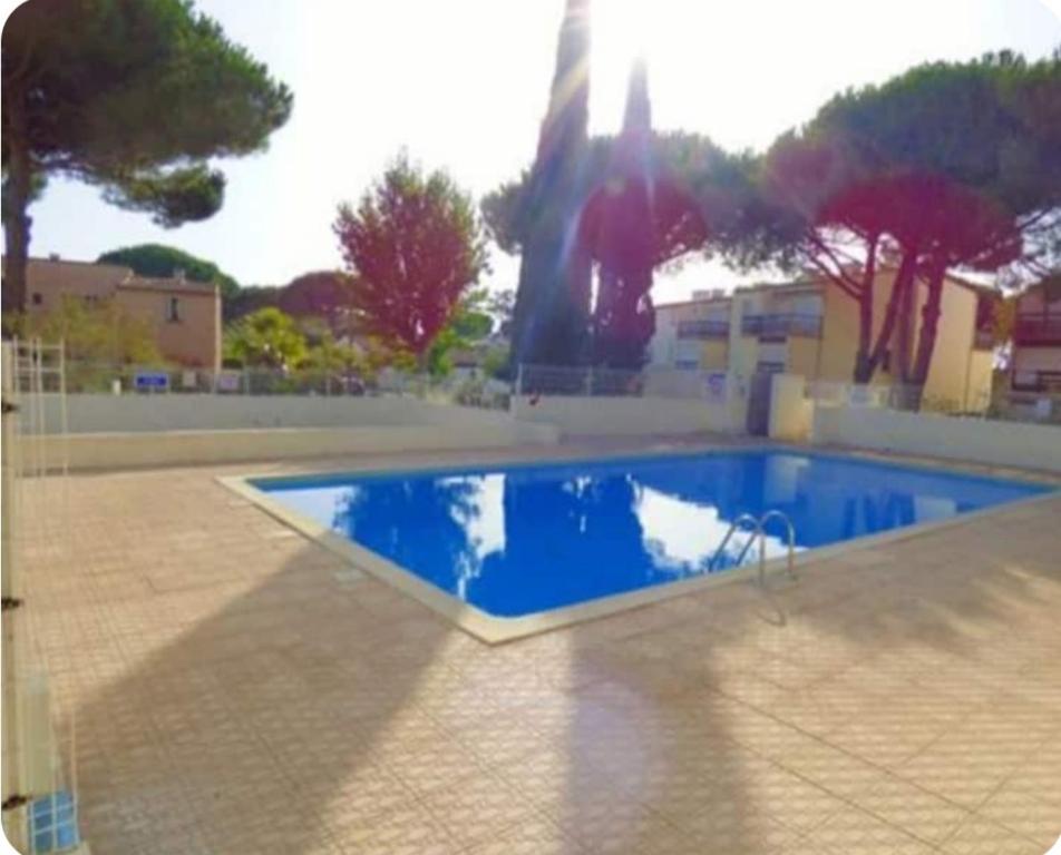 une piscine bleue avec des arbres et un bâtiment dans l'établissement Studio cabine Grau D Agde résidence avec piscine, au Grau-dʼAgde