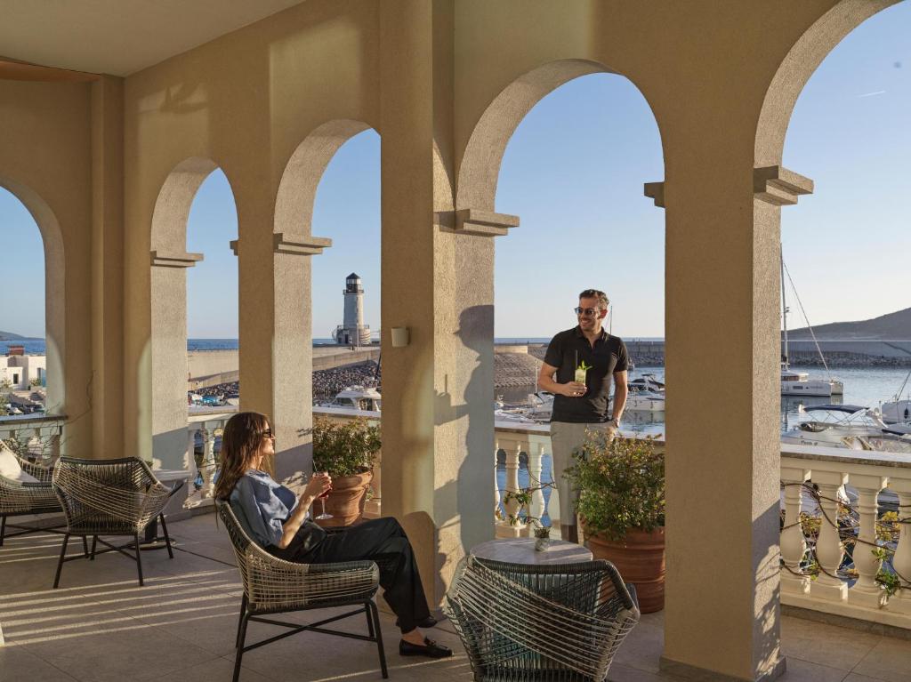 a man and a woman sitting on a balcony with a view of the ocean at The Chedi Luštica Bay in Tivat