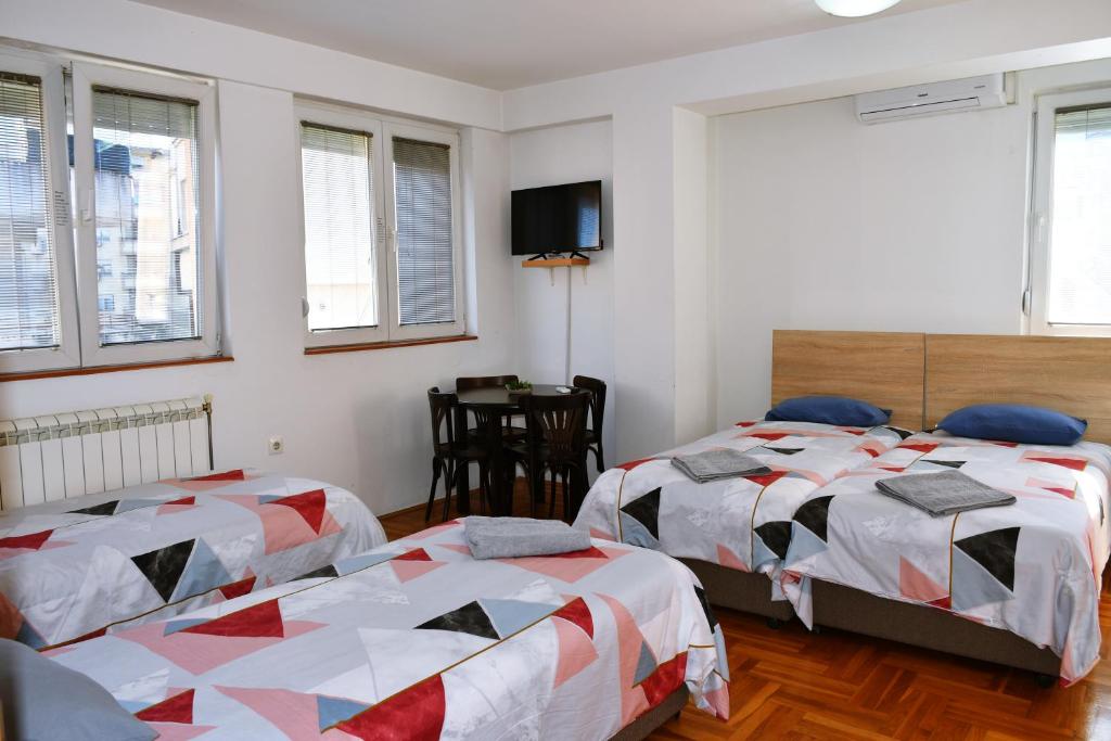 a bedroom with two beds and a tv on the wall at Guest House Sani in Skopje