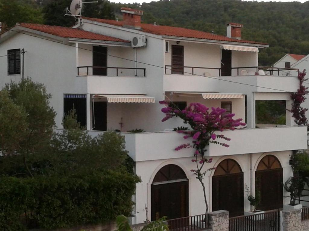 a white house with purple flowers in front of it at Apartments Villa Zvonimir in Slatine