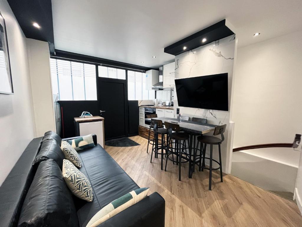 a living room with a black couch and a kitchen at Urban Flat 172 - Pretty Flat Gaite Montparnasse Cinema in Paris