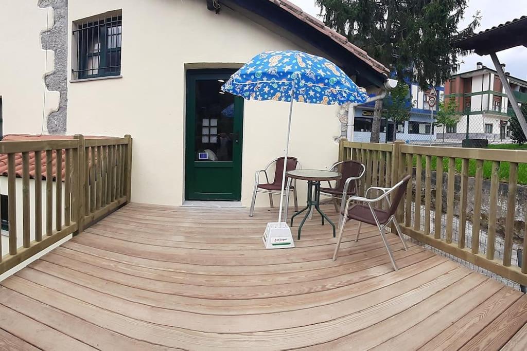 a wooden deck with a table and chairs and an umbrella at Pequeño apartament rural con un gran jardin. WIFI in Ispáster