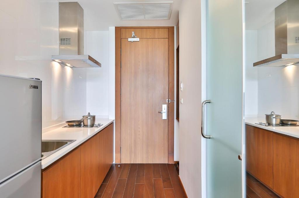 A compact galley kitchen with a refrigerator, hob, extractor and entry door.