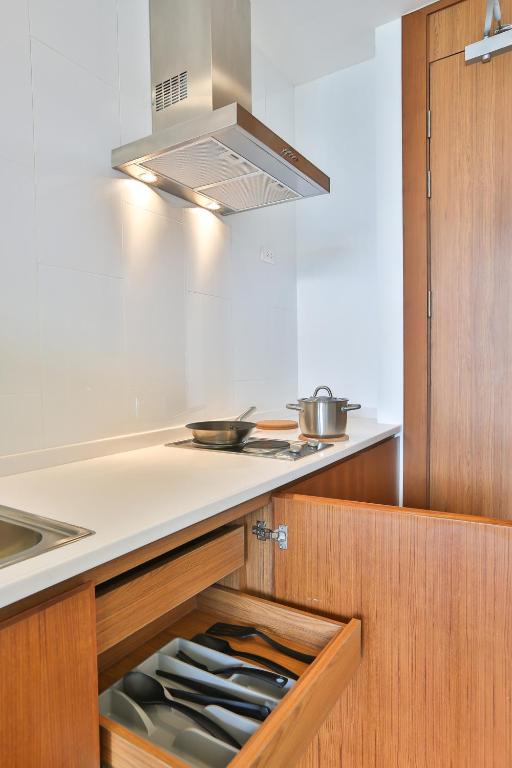 A close view of the kitchen hob, extractor and stocked utensil drawers.