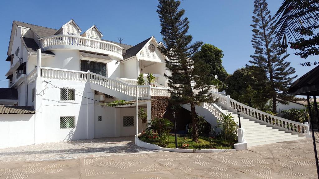 Casa blanca con escaleras blancas y árboles en #1 princess self catering apartments, 230mt to senegambia business strip., en Kololi