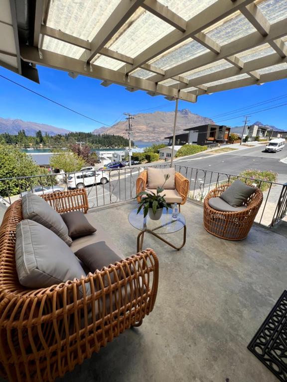 een patio met 2 rieten stoelen en een parasol bij Moon House in Queenstown