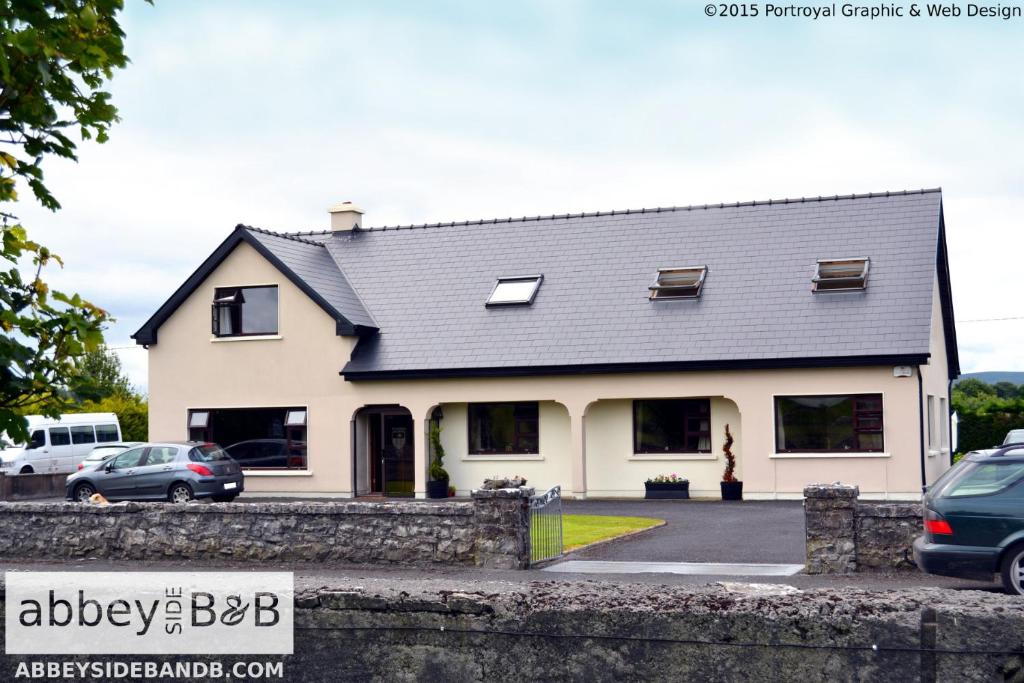 a white house with a black roof at Abbeyside B&B in Ballintober