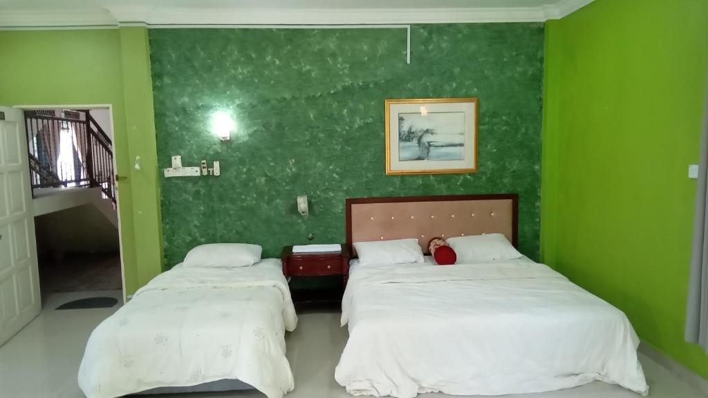 2 camas en una habitación verde con paredes verdes en D' Bunga Hotel Bukit Bunga Bilik Family Deluxe en Batu Karang