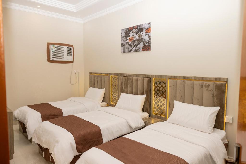a group of three beds in a room at فندق نبض المخلاف in Şāmitah