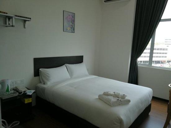 Schlafzimmer mit einem großen weißen Bett und einem Fenster in der Unterkunft hotel seri liny in Kuching