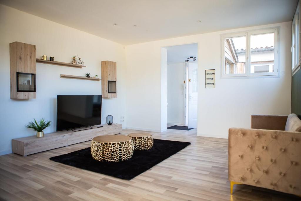 un salon avec une télévision et une table dans l'établissement Maison Rénové Spacieuse Cosy Jardin 8 Pers, au Mans