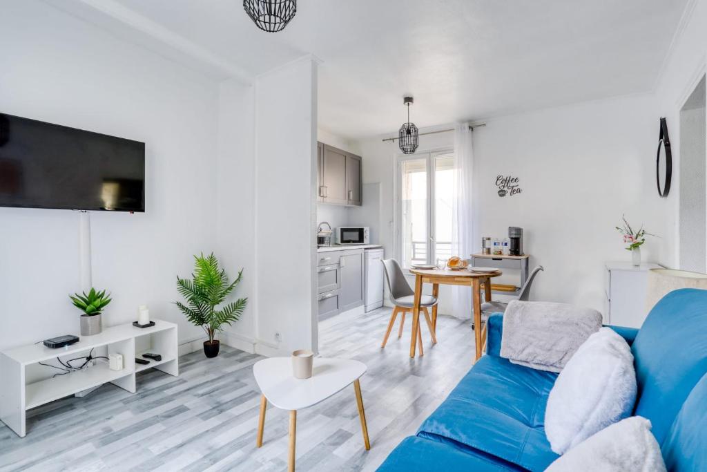 a living room with a blue couch and a kitchen at Magnifique Appart Cosy Rénové Gare 2 pers in Gagny