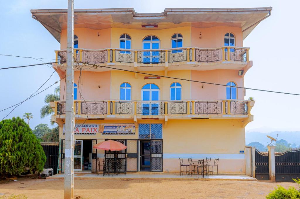 ein Gebäude mit blauen Fenstern und einem Balkon in der Unterkunft COMPLEXE GROUPE NJAYOU SARL-U (CGN HOTEL) in Mapara