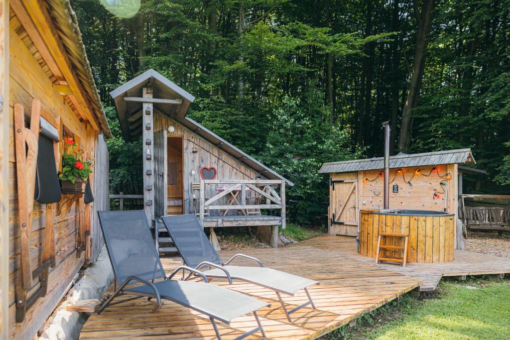 2 sillas en una terraza de madera junto a una cabaña en Alp Glamping Village, en Radovljica