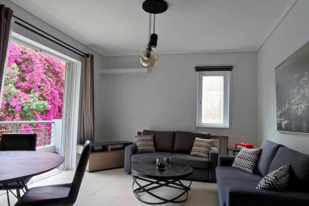 sala de estar con sofá, mesa y ventana en Seaside Haven - Alimos, en Atenas