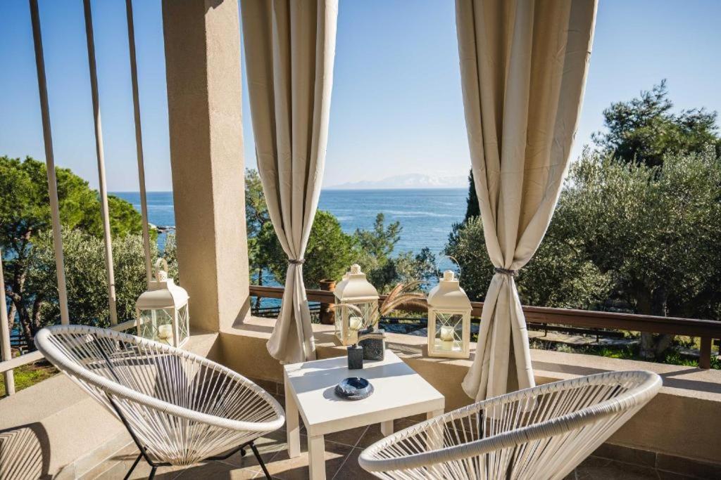 dwa krzesła i stół na balkonie z widokiem na ocean w obiekcie Our Luxury Houses - Suites w mieście Palaión Tsiflíkion