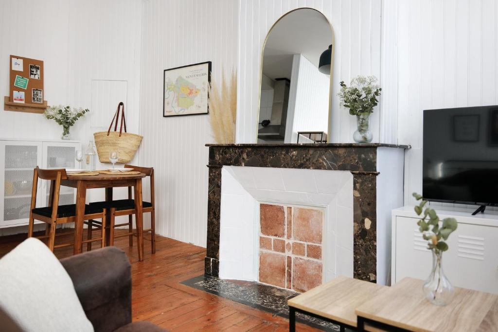 a living room with a fireplace and a table at Le Studio de la Bastide - Classé 2 étoiles - Libourne in Libourne