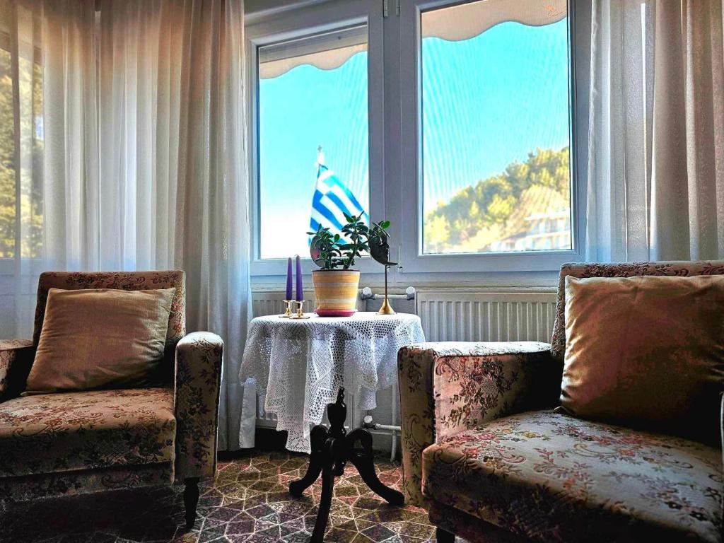 ein Wohnzimmer mit 2 Stühlen, einem Tisch und einem Fenster in der Unterkunft Villa Christina in Eleftheroúpolis