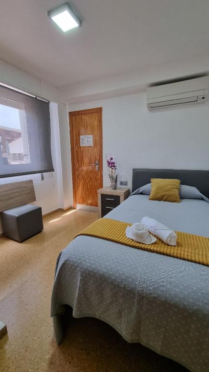 een slaapkamer met een groot bed en handdoeken bij Pension Colón in San Juan de Alicante