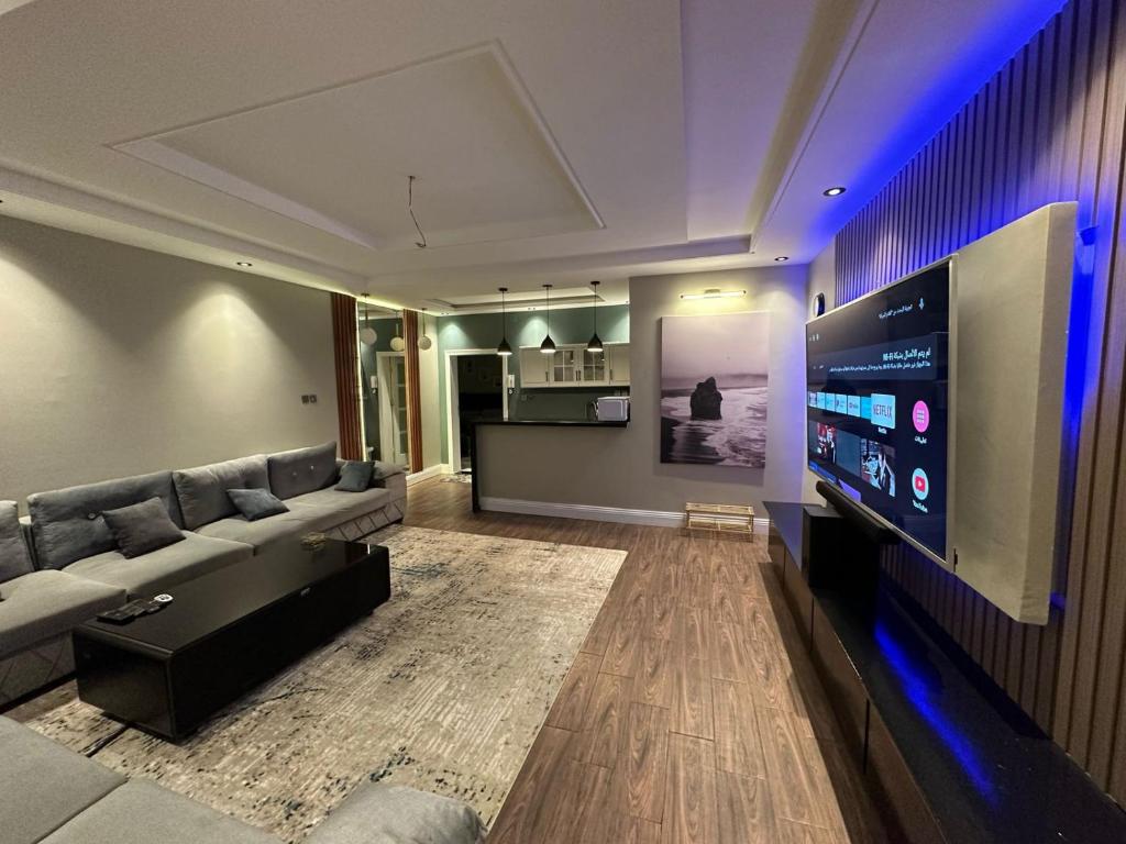 een woonkamer met een bank en een grote flatscreen-tv bij أجنحة لافينا الخاصة in Yanbu