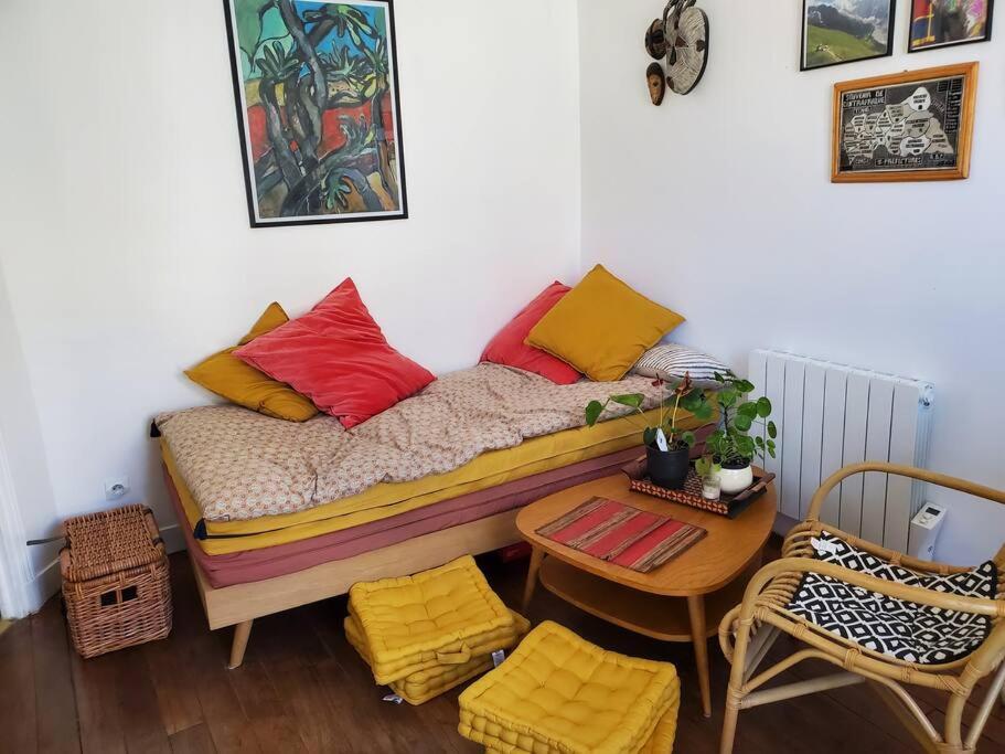 Cette chambre comprend un lit avec des oreillers colorés et une table. dans l'établissement Nid cosy au coeur de Saint-Denis, à Saint-Denis