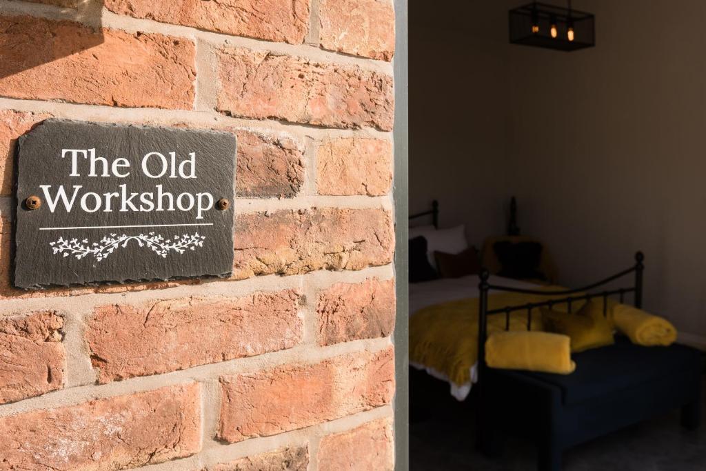 a brick wall with a sign that reads the old workshop at The Old Workshop in Higher Burwardsley