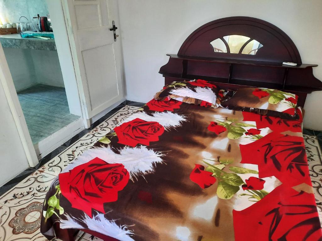 a bed with red roses bedding in a room at Chez Madam Rose in Le Morne