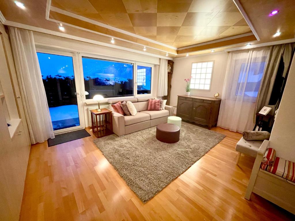 un soggiorno con divano e una grande finestra di Sunny-Nest, Garden Apartment a Leukerbad
